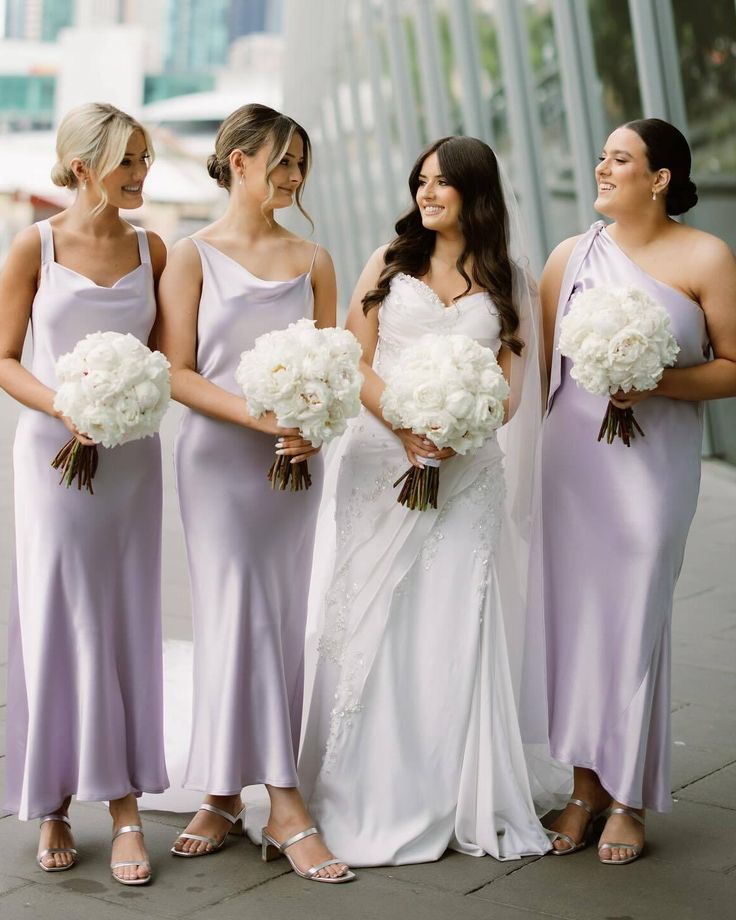 the bridesmaids are all dressed in lavender colored dresses and holding bouquets with white flowers