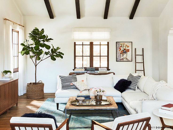 a living room filled with white furniture and lots of windows