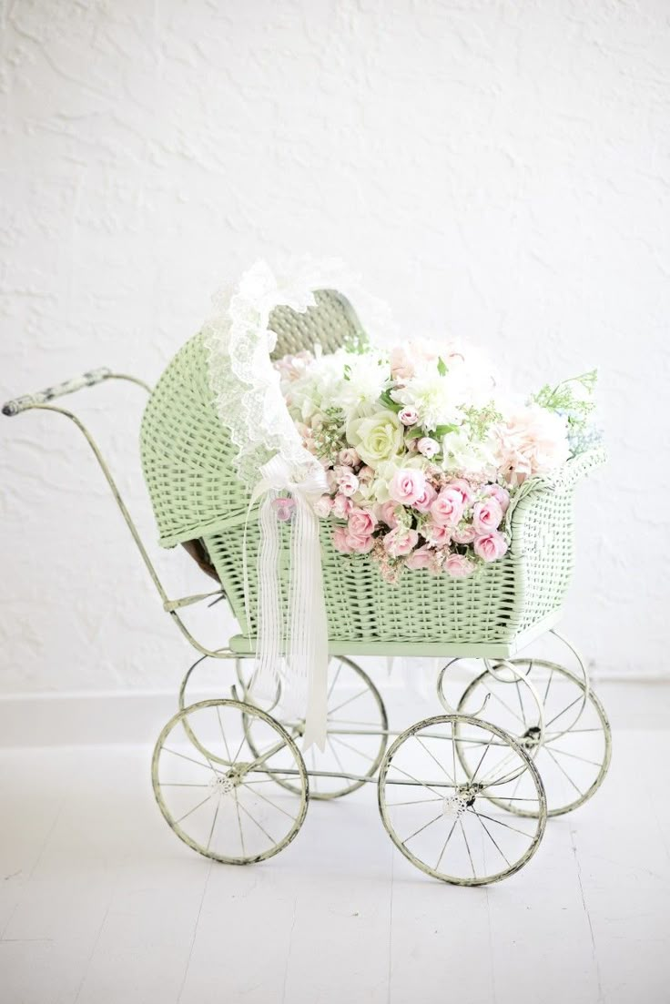 a baby's carriage with flowers in it on a white floor next to a wall