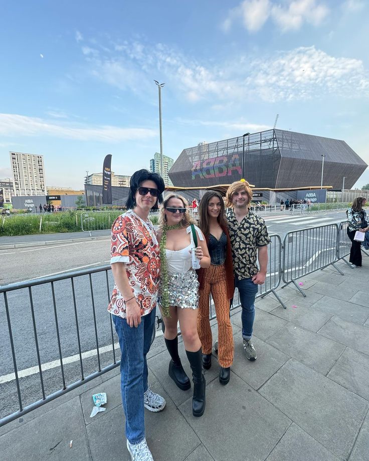 four people posing for the camera in front of a stadium