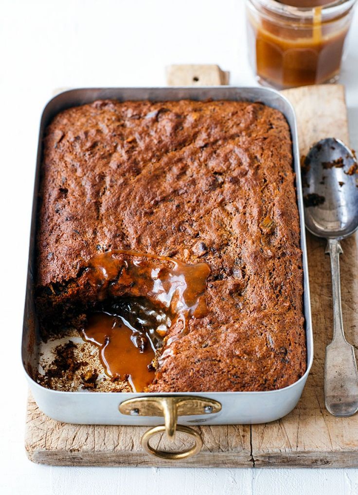 a close up of a cake in a pan on a cutting board with a spoon