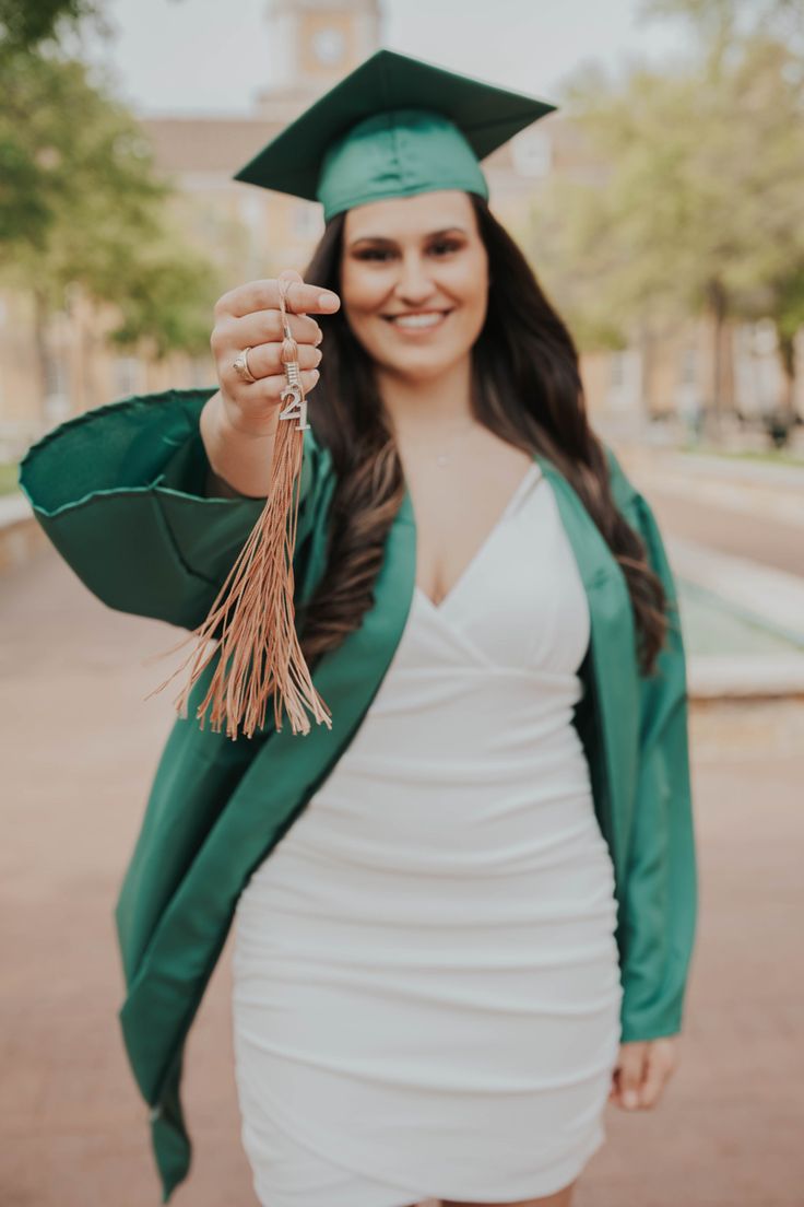 a woman wearing a graduation cap and gown holding a tassel in her right hand