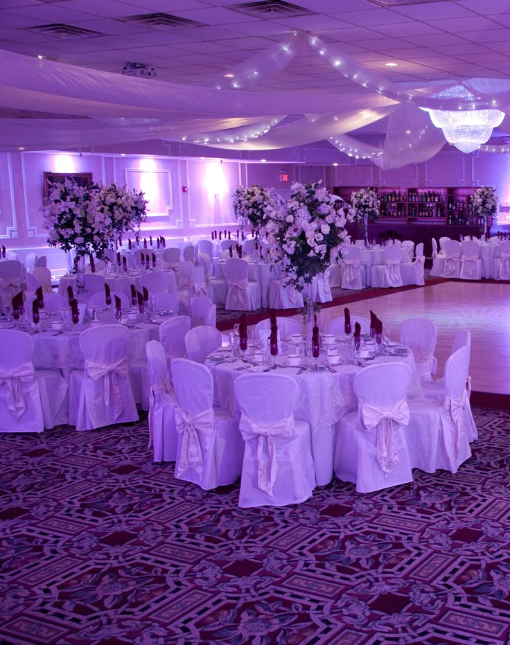 the banquet hall is set up with white linens and tables for an elegant event