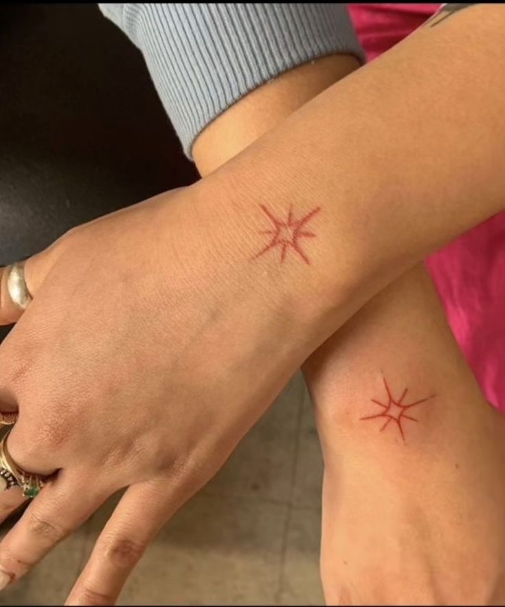 two people with matching tattoos on their hands and one is holding the other's hand