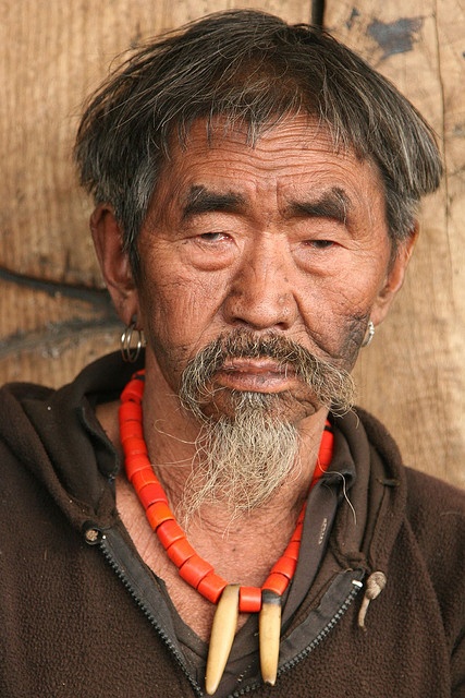 an old man with horns on his head wearing a red bead around his neck