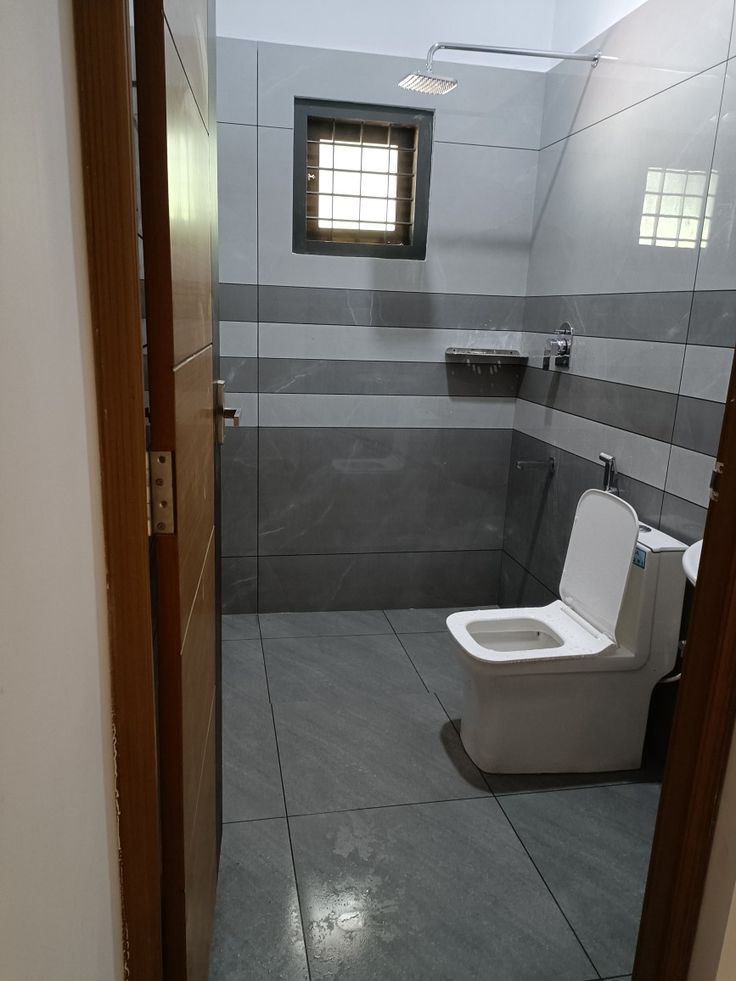 a bathroom that has a toilet in the middle of it with tile flooring and walls