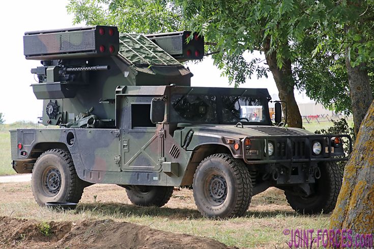 an army vehicle parked under a tree in the grass