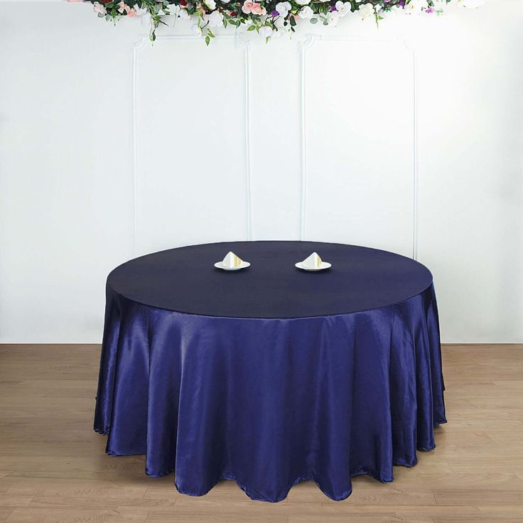 a round table with two white plates on it and flowers hanging from the ceiling above