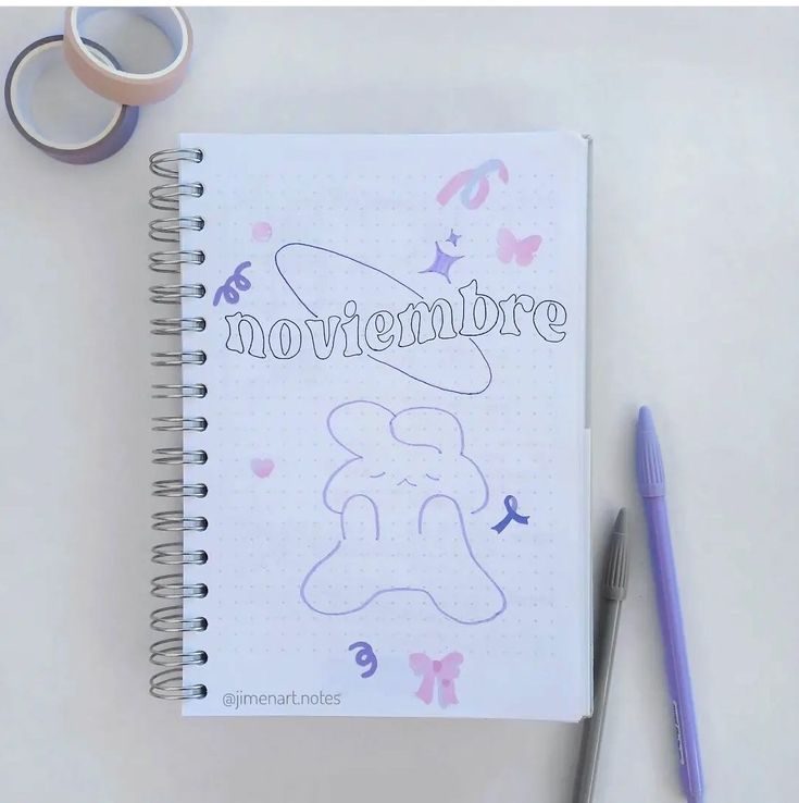 a notebook with the word movembere written in cursive writing next to a pair of scissors