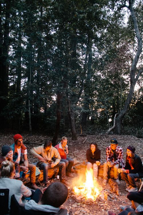 a group of people sitting around a campfire