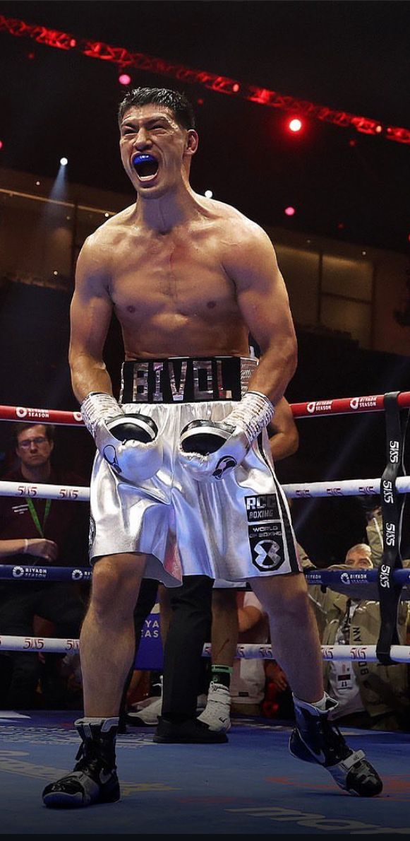 a man standing in the middle of a boxing ring with his mouth wide open and one hand on his hip