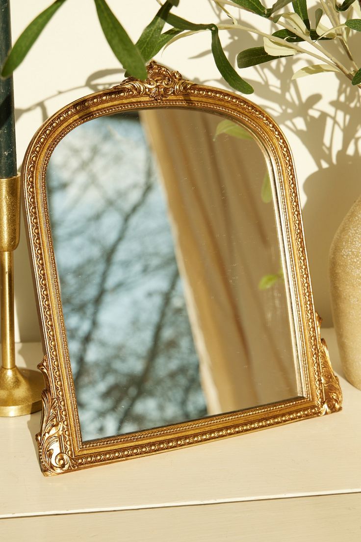 a mirror sitting on top of a table next to a vase