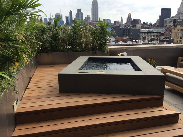 a hot tub sitting on top of a wooden deck next to a lush green plant