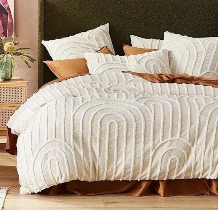 a bed with white and brown comforters in a bedroom next to a nightstand table