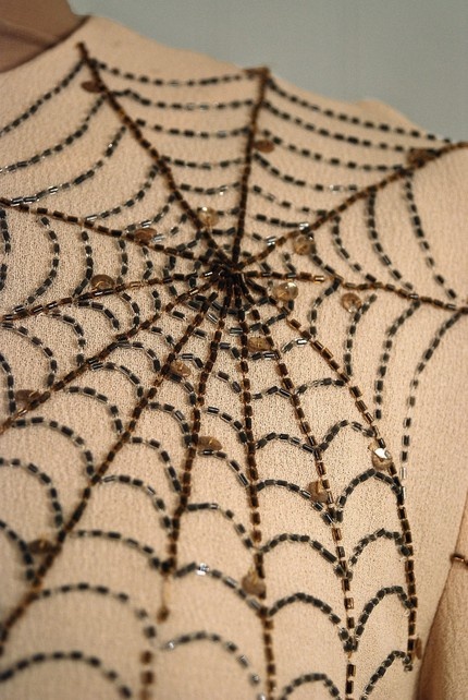 the back of a woman's dress with beaded spider webs on it