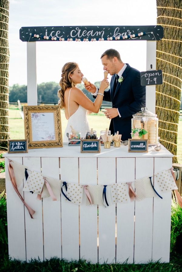 a bride and groom are standing in front of a sign that says ice cream bar