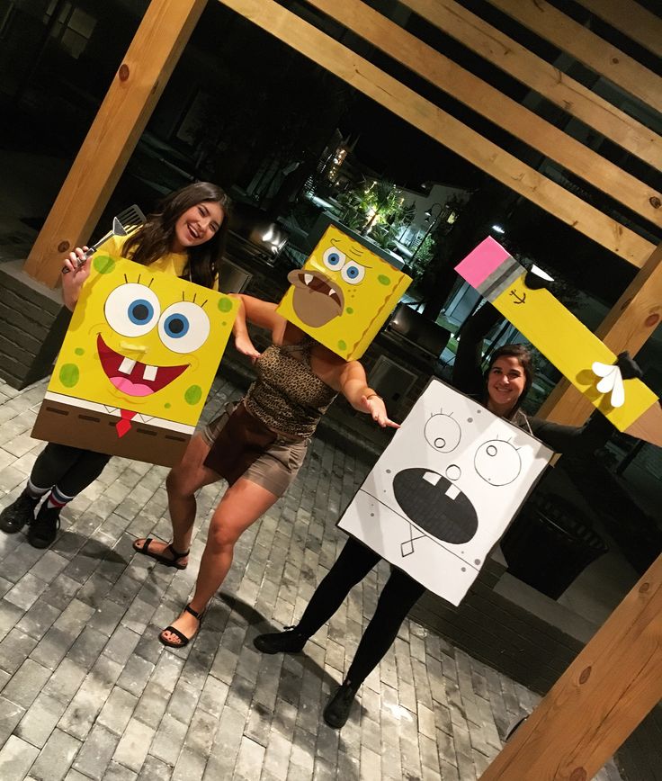 two women are holding cardboard boxes with faces on them and one is wearing a paper bag