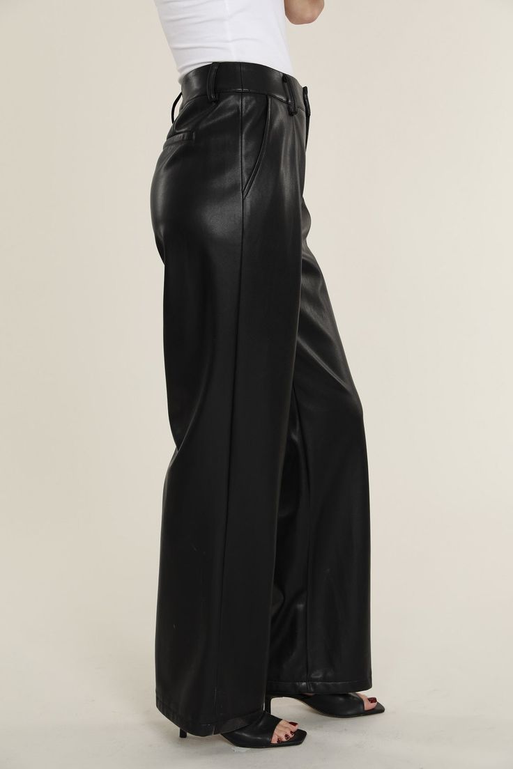 Elevate your professional outfits (or even just your everyday looks) with an edgy wardrobe staple like our Faux Leather Wide Leg Trouser Pants. Tailored to perfection, these wide legged trousers offer a relaxed yet polished vibe, ideal for curating a smart casual look. The sleek faux leather material lends a modern edge, while the wide leg cut ensures a comfortable, airy feel. Pair these with a crisp blouse or a casual tee to create versatile looks that transition effortlessly from office hours Chic Wide-leg Leather Pants For Workwear, Wide Leg Faux Leather Pants For Date Night, Date Night Wide Leg Faux Leather Pants, Sleek Wide-leg Leather Pants For Fall, Sleek Wide Leg Leather Pants For Spring, Trendy Wide Leg Dress Pants For Formal Occasions, Faux Leather Wide Leg Pants For Work, Wide Leg Faux Leather Work Pants, Trendy Wide Leg Formal Pants