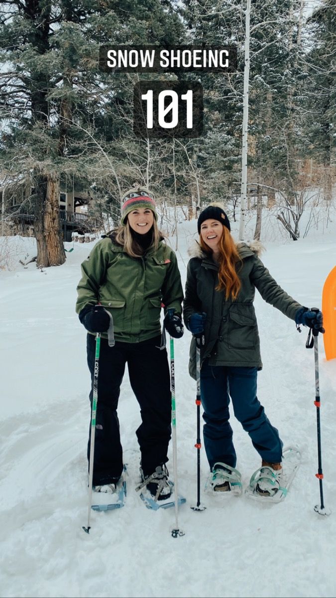 two women standing next to each other in the snow with skis on their feet