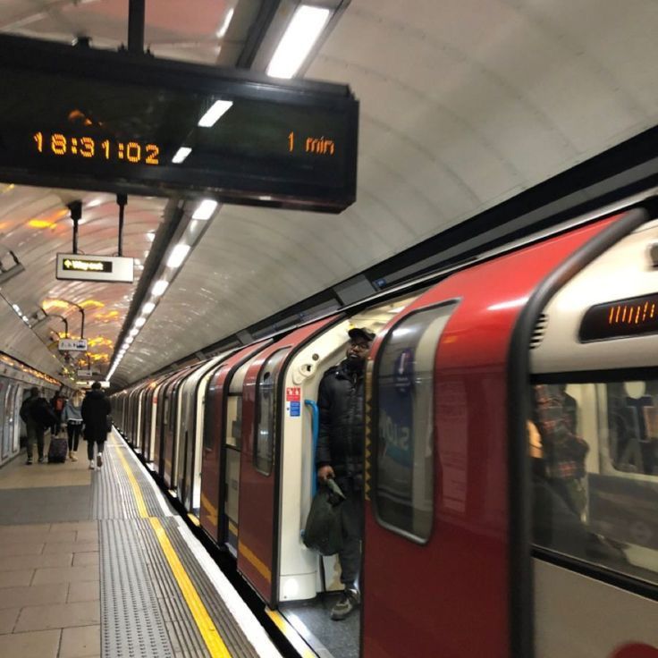 a subway train pulling into the station with people walking on the platform next to it