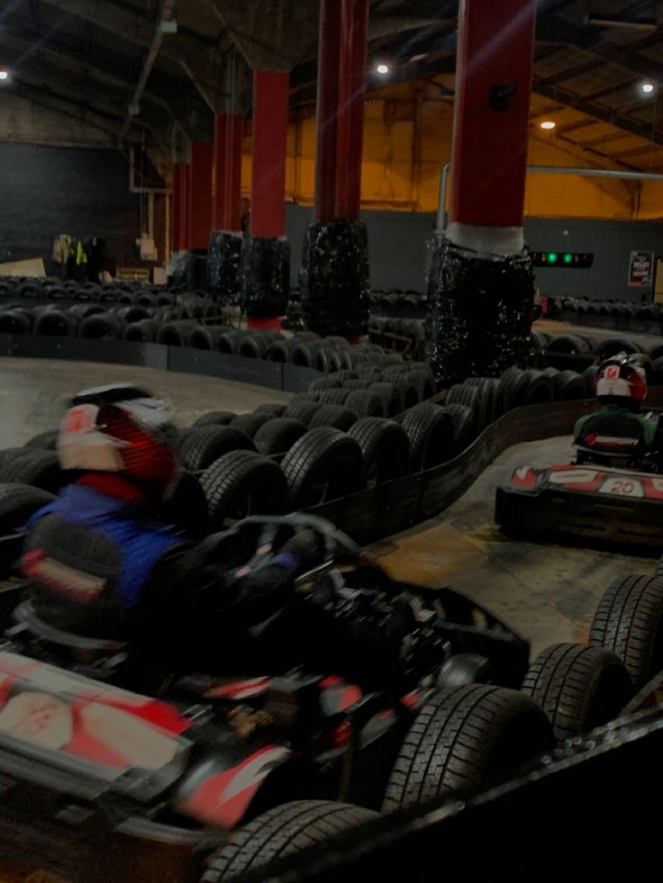 an indoor go kart racing track with several people in the back and one person driving