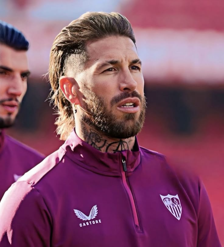 two men with long hair and beards standing next to each other on a field