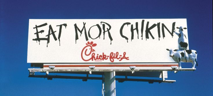 a sign that says eat more chicken on it with a cow statue in the background