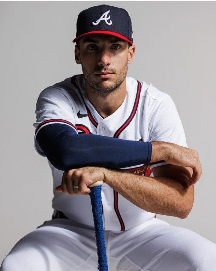 a baseball player is posing for a photo with his bat in hand and wearing a hat