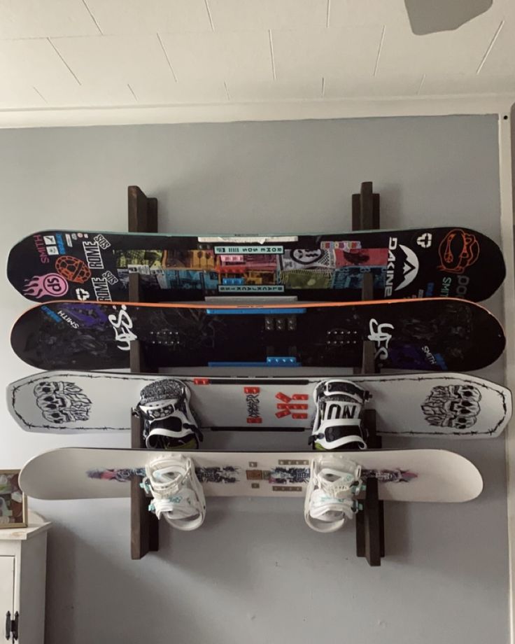 three snowboards mounted to the side of a wall with two pairs of shoes on them