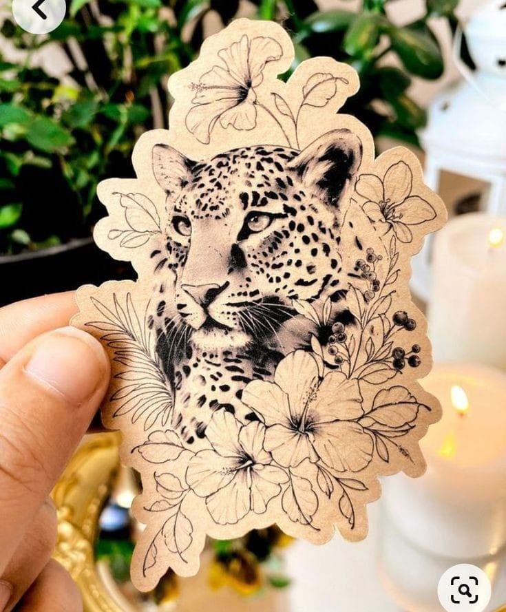 a person holding up a sticker with a drawing of a leopard and flowers on it