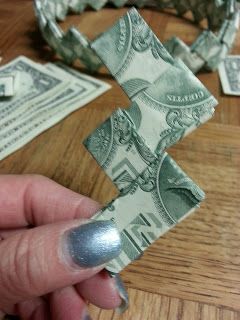 a person is holding money in front of them on a wooden table with other dollar bills