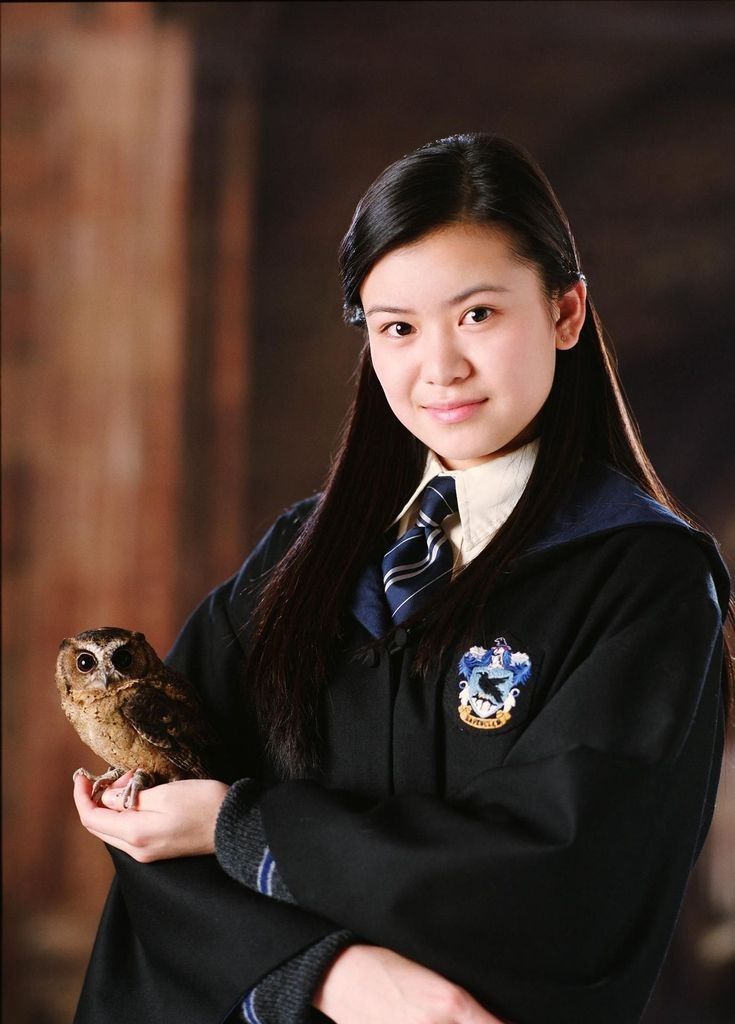 a young woman holding an owl in her hands while wearing a harry potter outfit and smiling