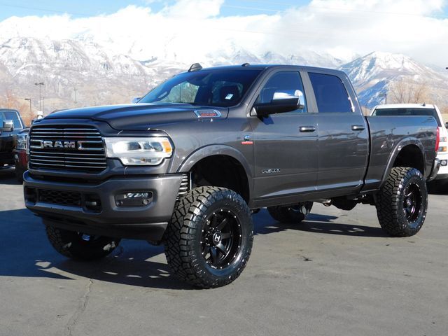 a large gray truck parked in a parking lot next to other trucks and snow covered mountains