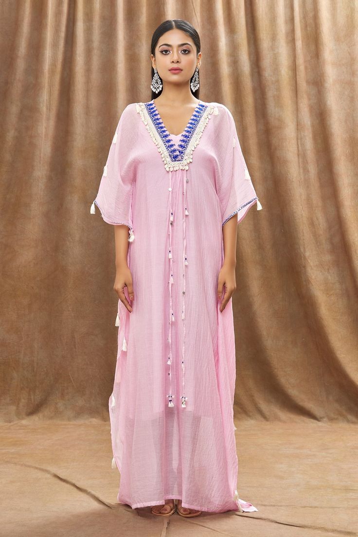 Pink mulmul chanderi kaftan with thread embroidery on the neck, embellishment with mirrors, shell lace and tassels on the hem. Paired with a sleeveless slip.
Component: 2
Pattern: Embellishment
Type Of Work: Mirror, Thread and Shells Lace Work
Neckline: V Neck
Sleeve Type: Batwing Sleeves
Fabric: Mulmul Chanderi
Color: Pink
Other Details: 
Tasselled strings attached on the front placket)
Occasion: Resort - Aza Fashions V Neck Kaftan, Kaftan For Women, Pink Mirror, Thread Embroidery, Batwing Sleeve, Bat Wings, Aza Fashion, Sleeve Type, Tassels