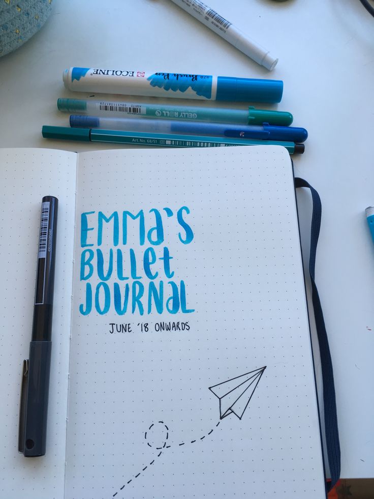 an open notebook with writing on it and some pens next to it, along with other office supplies