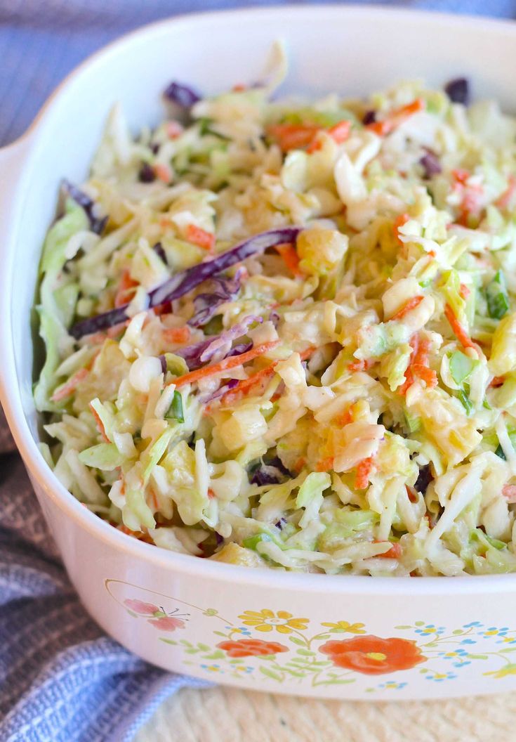 a white bowl filled with coleslaw salad on top of a blue and white towel