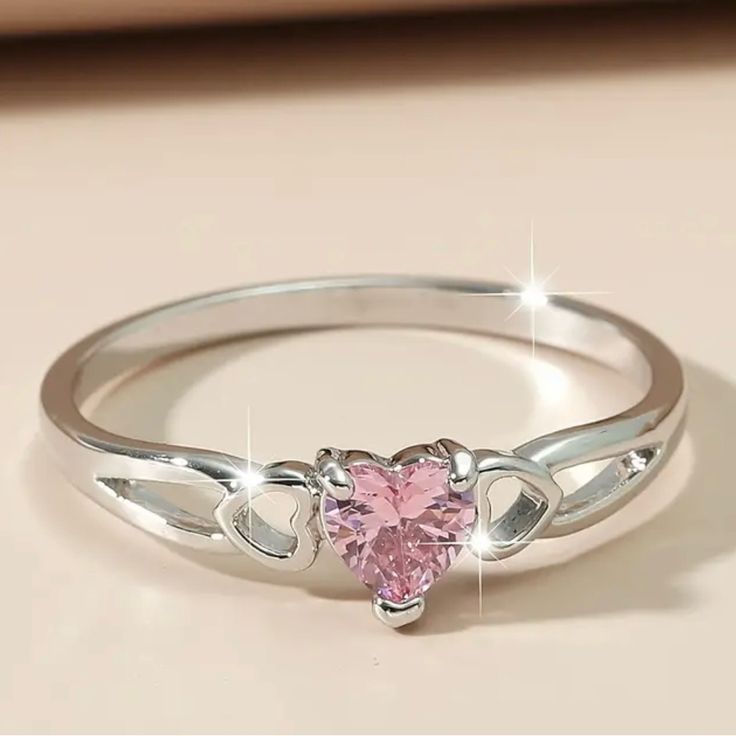 a heart shaped pink diamond ring on top of a table