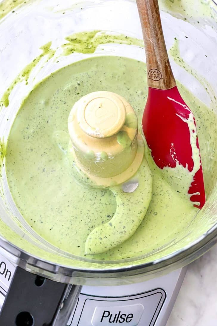 a blender filled with green liquid and a wooden spoon