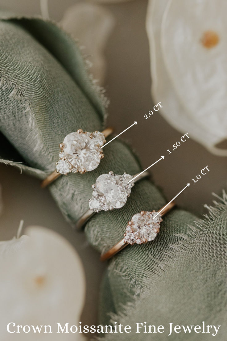 three different types of wedding rings on top of a green cloth with the names crown moosantee fine jewelry