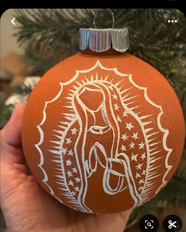 a hand holding an ornament with the image of mary on it