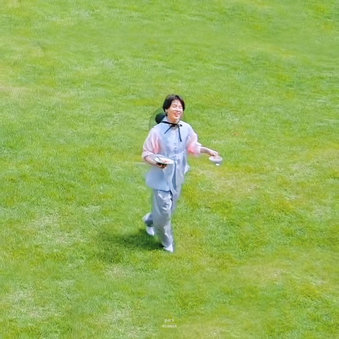 a woman is running on the grass with a frisbee in her hand,