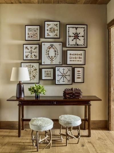 two stools sit under a table with pictures on the wall above it and below them