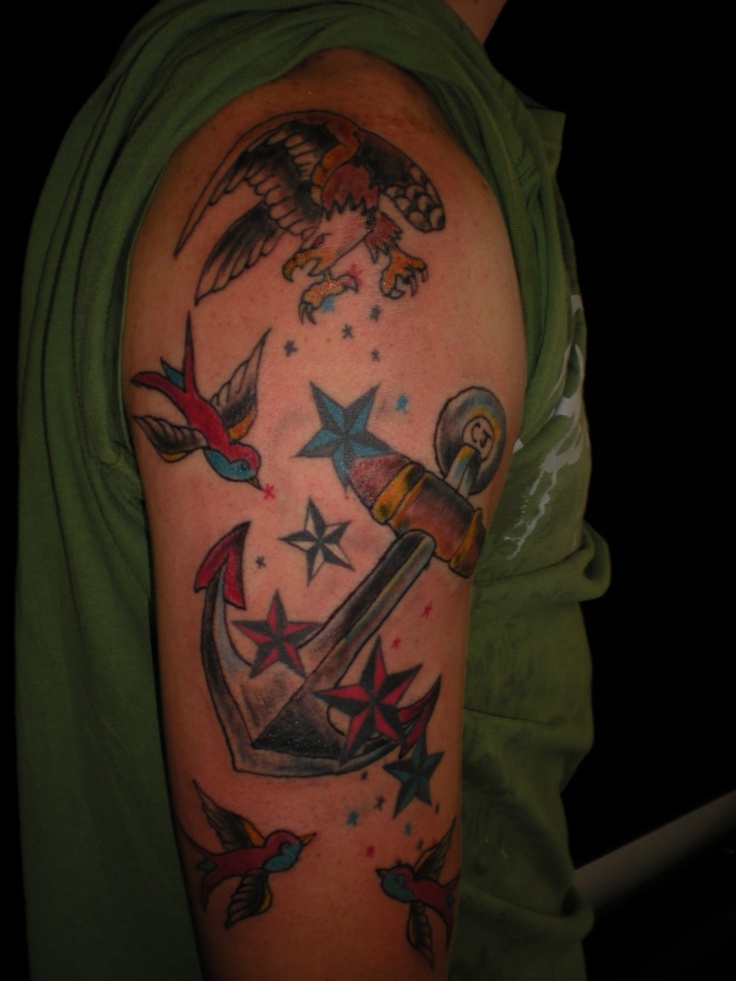 an anchor with birds and stars around it on a man's upper half sleeve