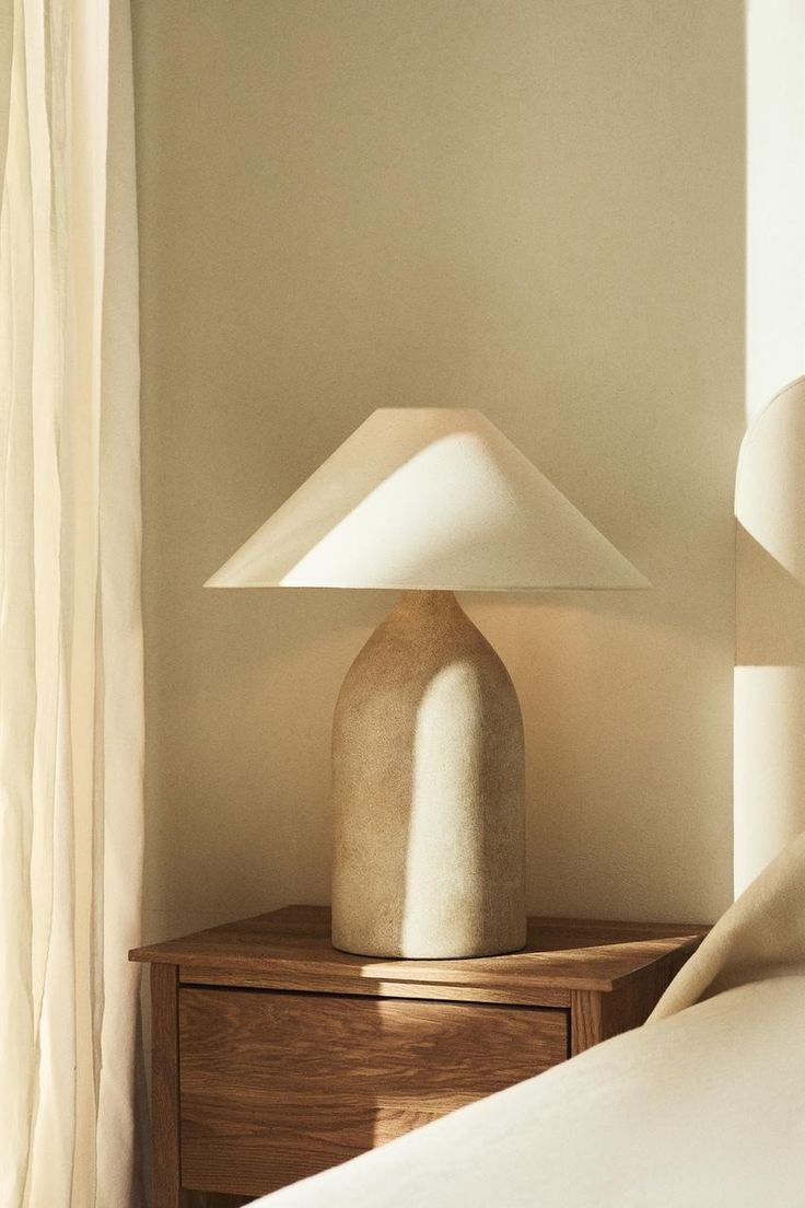 a white lamp sitting on top of a table next to a bed