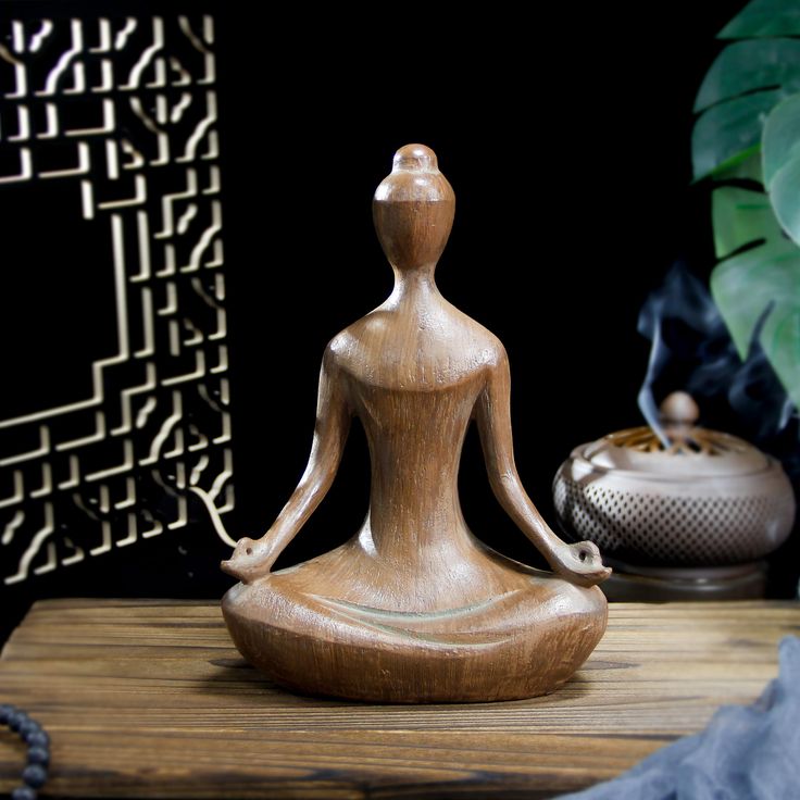 a buddha statue sitting on top of a wooden table next to a potted plant