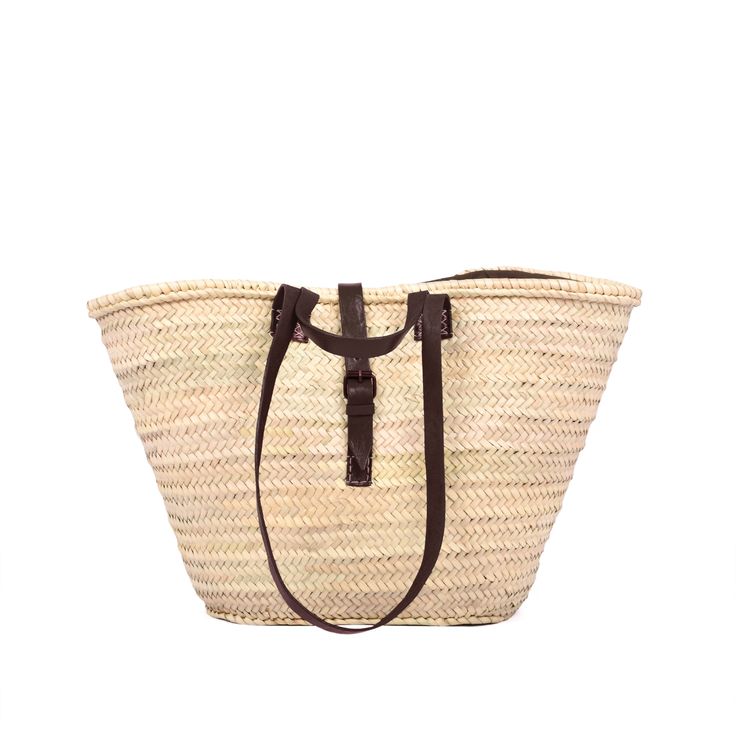 a straw bag with leather handles on the front and side, sitting against a white background