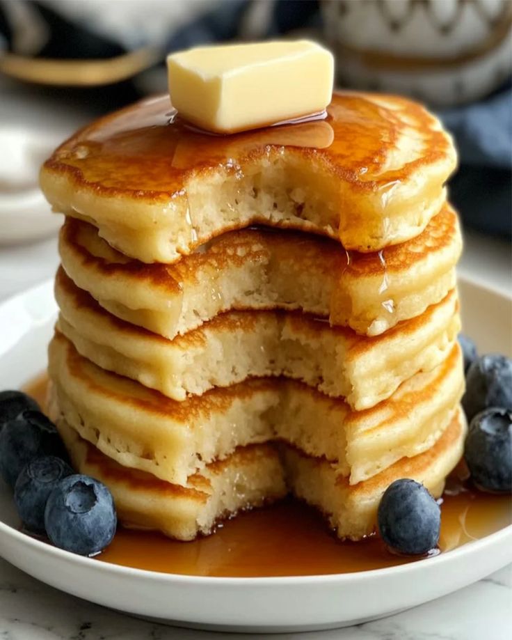 a stack of pancakes with butter and blueberries