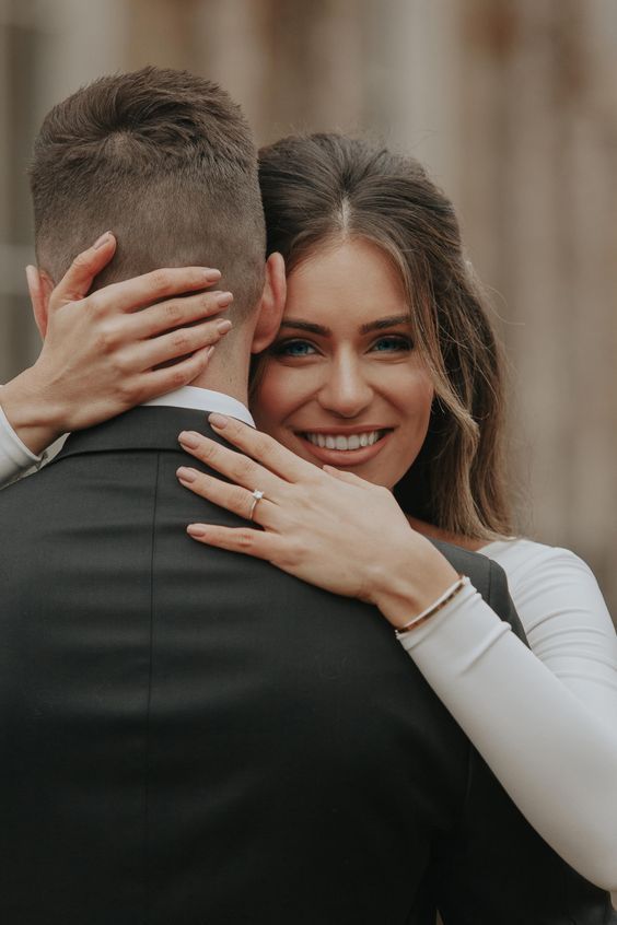 a man and woman hugging each other in front of a building