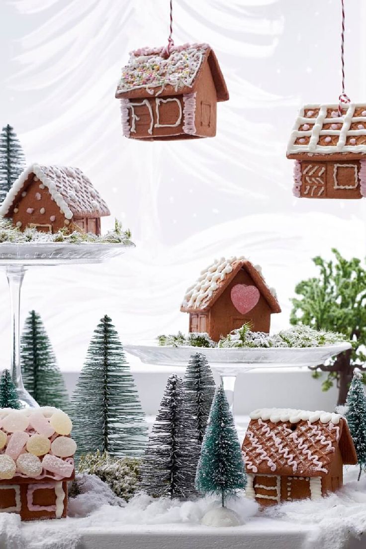 gingerbread houses and trees are hanging from strings in front of the snow covered landscape