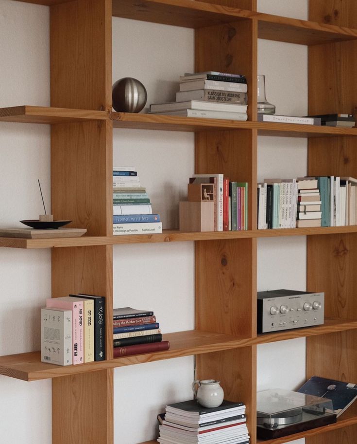 a bookshelf filled with lots of books next to a wall mounted record player